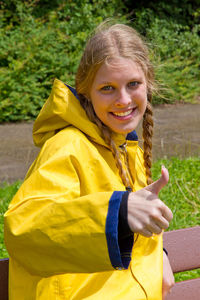 Portrait of smiling young woman showing thumbs up sign