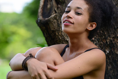 Portrait of woman looking away while sitting on tree