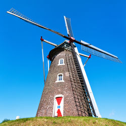 Low angle view of traditional windmill against blue sky