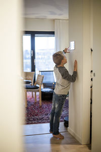 Full length of boy using digital tablet mounted on wall at modern home