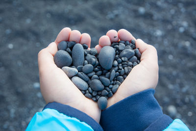 Hands holding small black stones, heart shaped