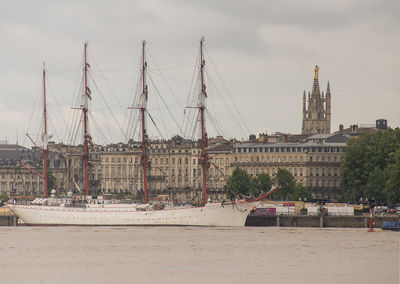 Sailboats in river against buildings in city