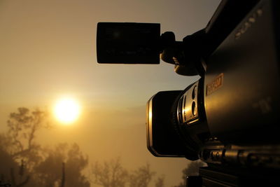 Low angle view of camera against sky during sunset