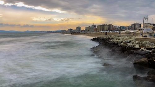 Scenic view of sea and buildings against sky during sunset