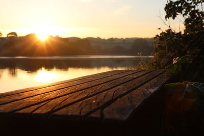 Wooden plank at lake during sunset
