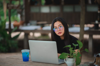 Portrait of woman using phone while sitting on table