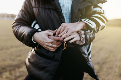 Couple holding hands with engagement rings