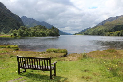 Scenic view of bench and lake and mountains against sky