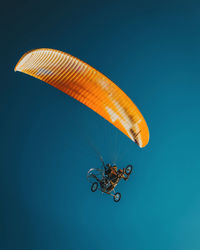 Low angle view of person paragliding against blue sky