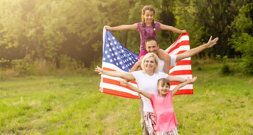Happy family with the flag of america usa at sunset outdoors