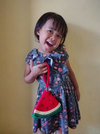 Portrait of smiling girl standing against wall