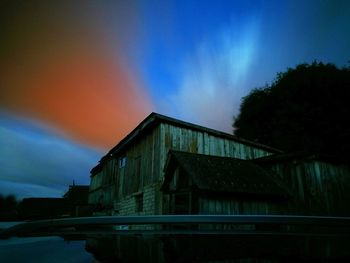 Illuminated factory against sky at sunset