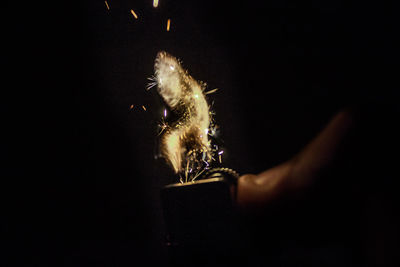 Close-up of hand holding cigarette against black background
