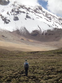 Rear view of woman walking towards snowcapped mountain during winter