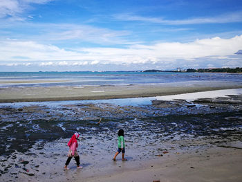 Rear view of people on beach against blue sky