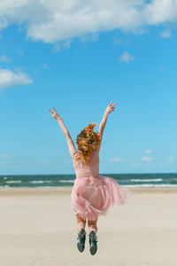 Full length of woman at beach against sky jumping 