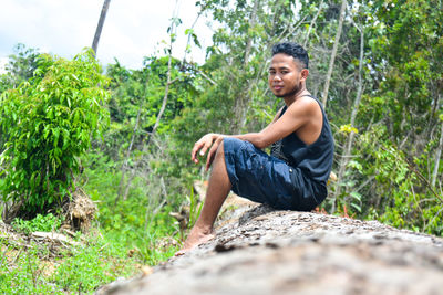 Young man sitting on rock