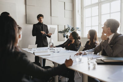 Male entrepreneur conducting business meeting with team in board room at office