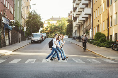 Side view of teenagers crossing road in city