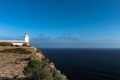 Lighthouse by sea against sky