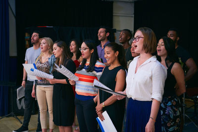 Multi-ethnic male and female students singing in choir at auditorium