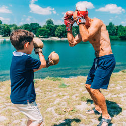 Full length of shirtless man holding water