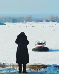 Rear view of man standing on snow covered landscape
