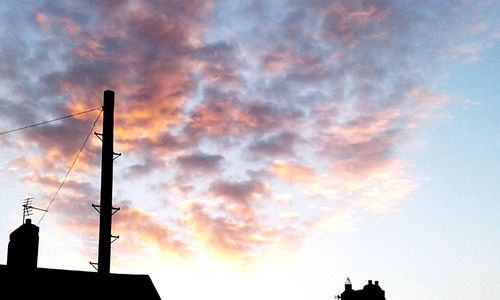 Low angle view of silhouette building against cloudy sky