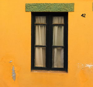 Traditional portuguese window with a green top inserted in a yellow wall