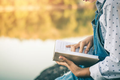 Midsection of woman holding paper outdoors