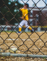 Close-up of baseball seen through chainlink fence