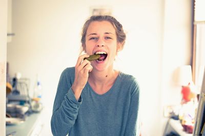 Portrait of smiling young woman eating food at home