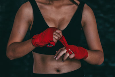 Midsection of woman holding red standing against blurred background