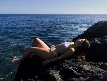 Woman relaxing in sea against sky