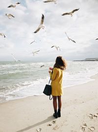 Full length rear view of woman standing on beach