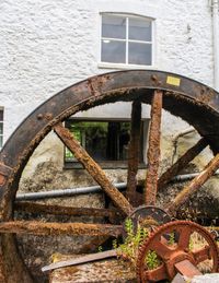 Rusty water wheel against building