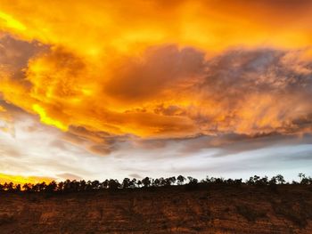 Scenic view of dramatic sky over land during sunset