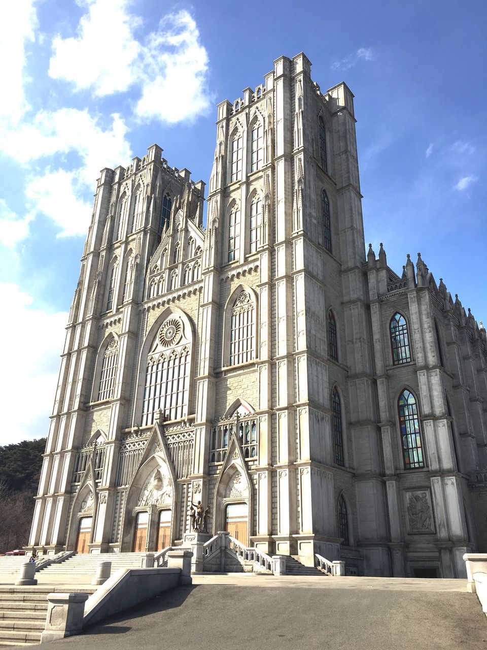 architecture, built structure, building exterior, low angle view, sky, church, place of worship, religion, cloud - sky, facade, history, cloud, spirituality, famous place, day, city, blue, travel destinations, sunlight