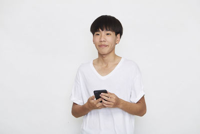 Mid adult man using smart phone against white background