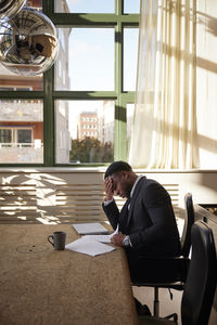 Side view of young woman sitting on chair at home