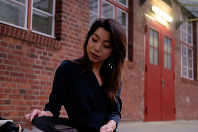 Full length of woman sitting against brick wall