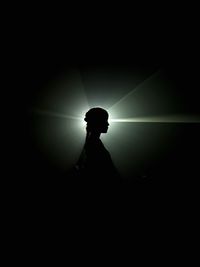 Side view of silhouette woman standing in darkroom