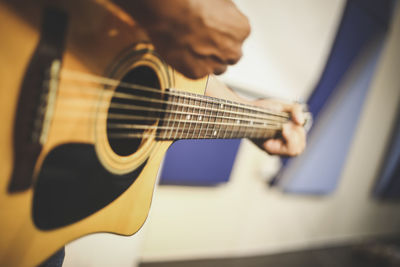 Cropped hand playing guitar in studio