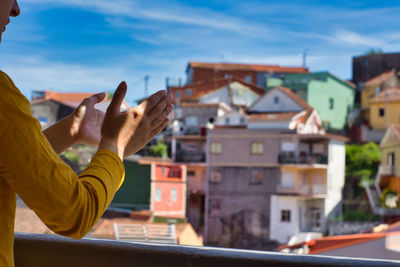 Midsection of man holding umbrella against buildings