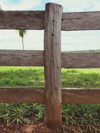 Close-up of wooden post on field against sky