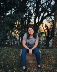 Portrait of young woman smiling while sitting at park