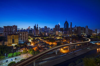 Illuminated cityscape against clear blue sky