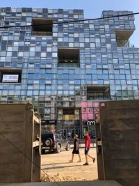 People walking on street by modern buildings in city