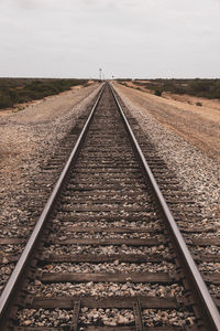 Railroad tracks on field against sky