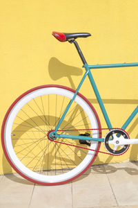 Bicycle parked against yellow wall